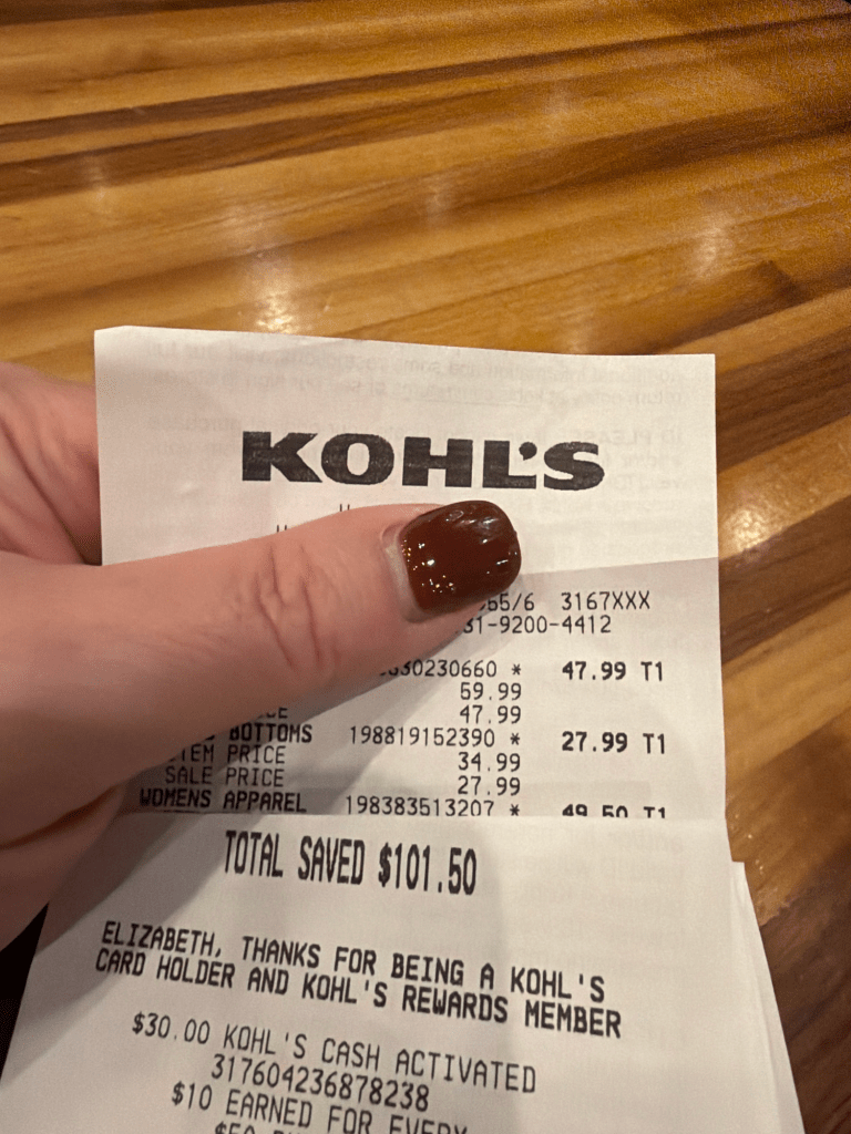 Close-up of a hand holding a Kohl’s receipt showing a total savings of $101.50.