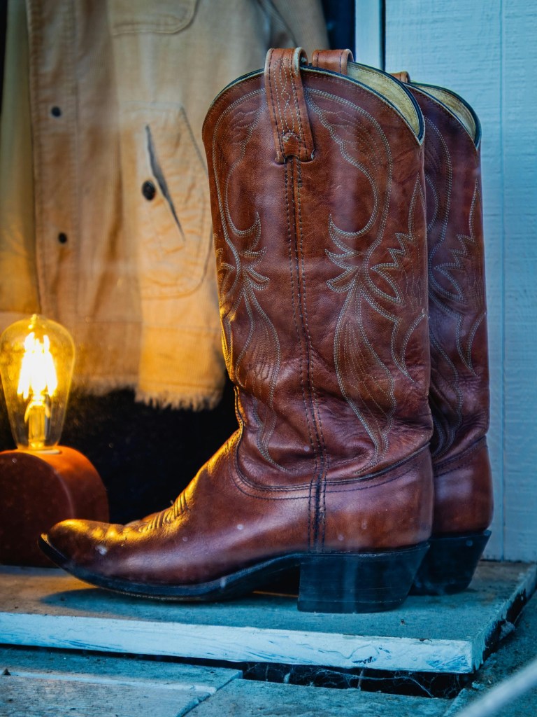 Pair of brown leather cowboy boots resting by a doorway.