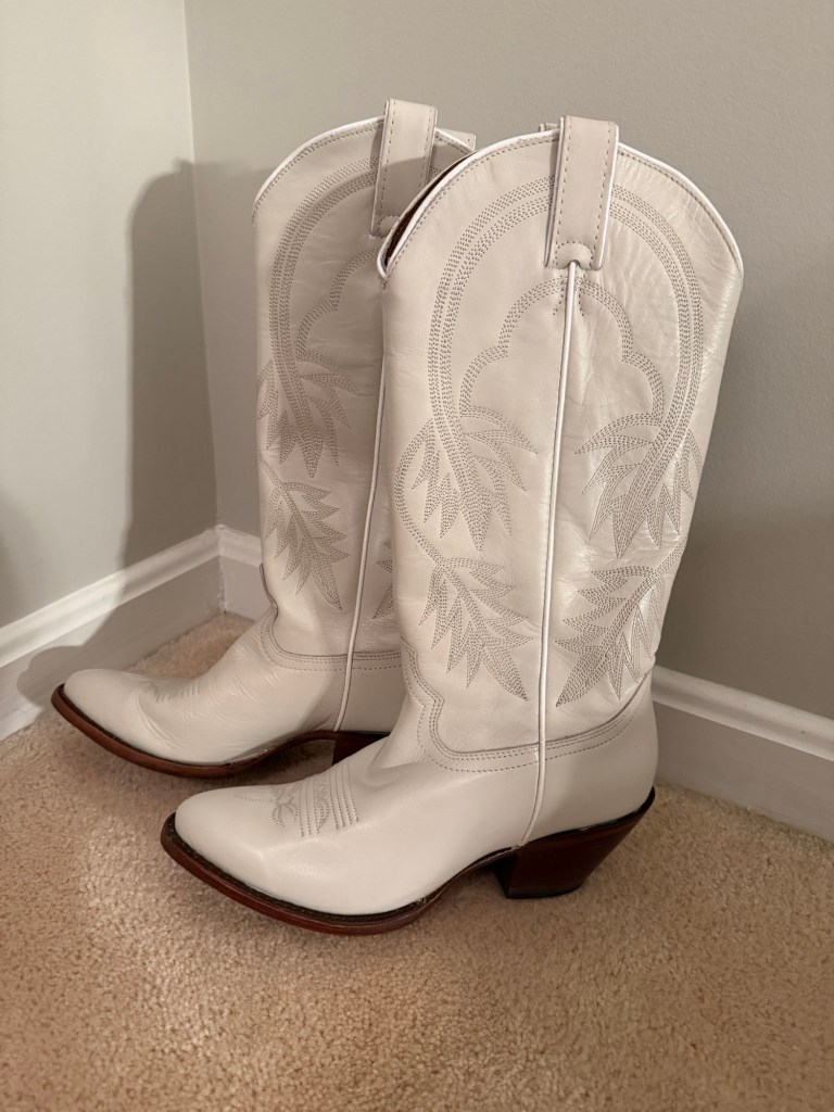 White cowboy boots, worn once, standing unused.